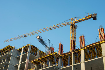 Tower crane on the construction of a new building with a blue sky
