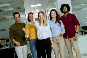 Group of young excited business people with hands up  standing in office