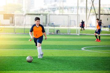 Soccer player speed run to shoot ball to goal on artificial turf.