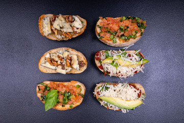 Appetizer bruschetta with cheese, honey, walnut and other ingredients on black background. Close-up. Italian food.