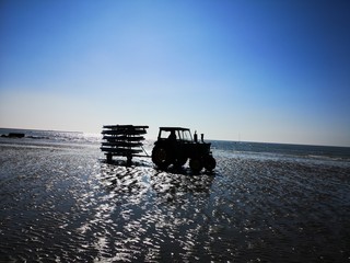 Fototapeta na wymiar Tractor carrying of windsurfers from the beach in Wimereux by a blinding sun