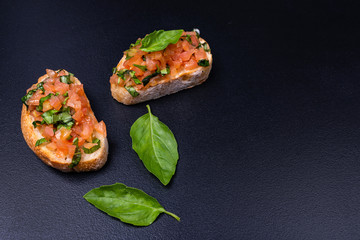 Tasty savory tomato Italian appetizers, or bruschetta, on slices of toasted baguette garnished with basil.
