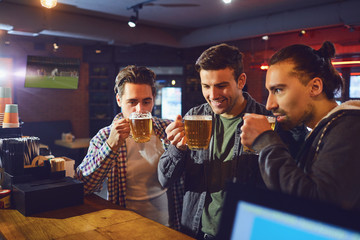 Friends drink beer from glasses in the bar.