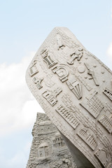 A sculpture showing various things under a blue cloudy sky