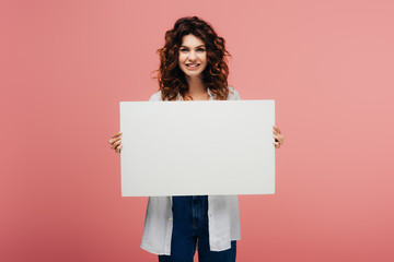 happy young woman holding blank placard while standing on pink