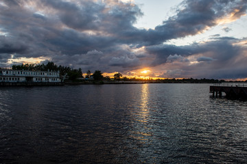 Obraz premium colorful sunset over the sea lake with dark red clouds