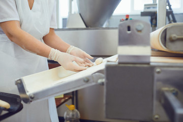 The hands of a woman working on the equipment make the dough for bread