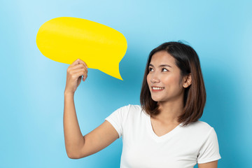 Portrait of young girl holding a empty yellow speech bubble isolated on blue background