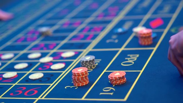 A table with a roulette in a casino. The croupier gives out a prize. Gambling for money. People make bets on roulette. Underground Casino