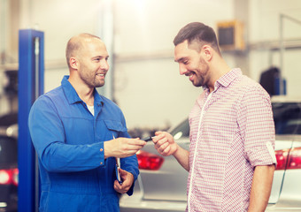 auto service, repair, maintenance and people concept - mechanic with clipboard giving key to happy smiling man or owner at car shop