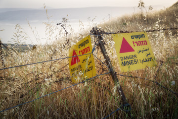 Yellow warning sign next to a mine field, close to the border with Syria, in the Golan Heights,...