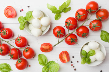 The ingredients for a Caprese salad. Basil, mozzarella balls and tomatoes on a white background with copy space.