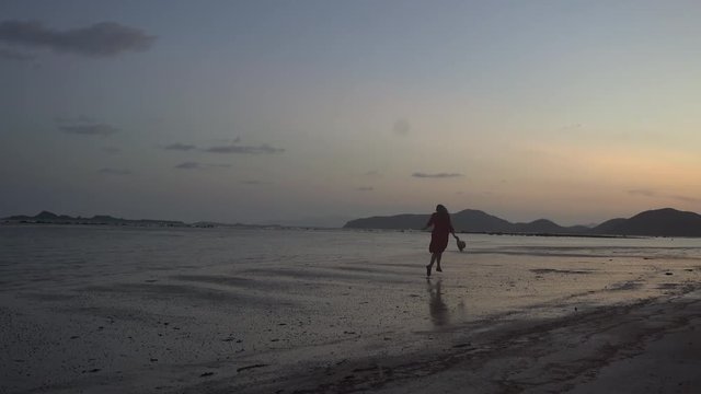 Beautiful girl on the beach in sunset 4k. Silhouette of young woman model runs on the tropical beach sunset slow motion. Jumps around celebrating freedom, life love, success concept. 