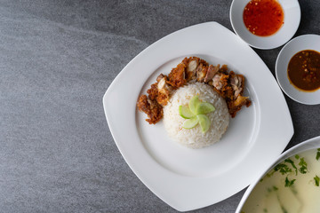 Hainanese chicken rice or rice cooked in chicken broth with fried chicken in the white dish.