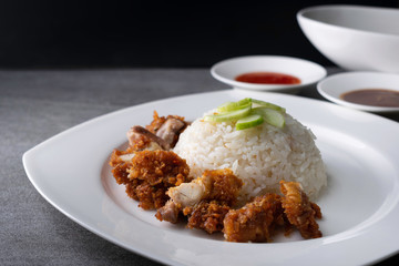 Hainanese chicken rice or rice cooked in chicken broth with fried chicken in the white dish.