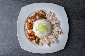 Hainanese chicken rice or rice cooked in chicken broth in the white dish.