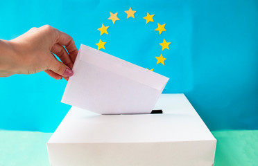 Voting slip being placed by a  hand into a ballot box with the European Union flag in the background