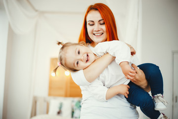 Beatuful ginger mother playing with daughter. Little girl have fun at home.