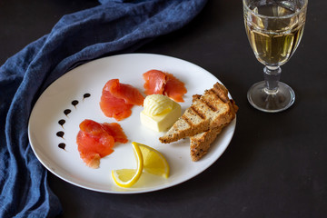 Trout, butter, bread and white wine. Dark background