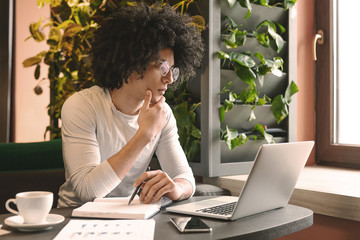 Confident young man working on laptop sitting in cafe