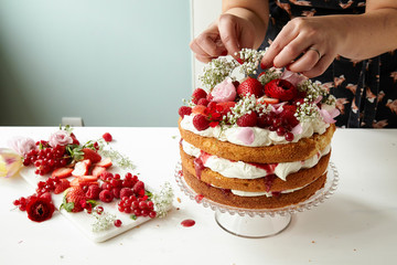 Victoria Sponge layer cake being decorated and filled with fresh cream and fruit coulis