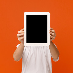Little boy hiding his face behind digital tablet