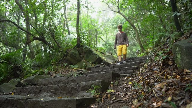 Casually Dressed Man Walking Down Stone Steps on Hiking Path in Asian Jungle