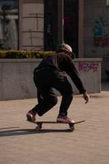 Young guys in stylish clothes ride a skateboard in the park.