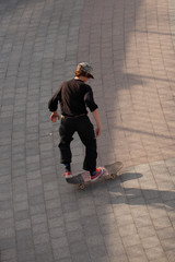Young guys in stylish clothes ride a skateboard in the park.