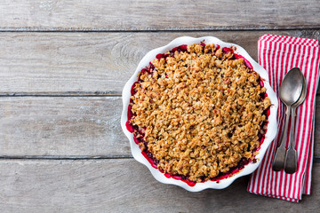 Berry crumble in white baking dish on grey wooden background. Top view. Copy space.