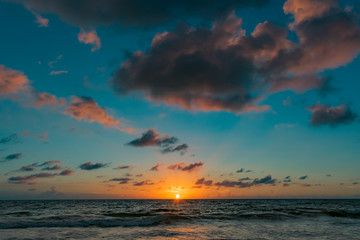 Fototapeta na wymiar rising orange sun in the dark blue sky over the ocean