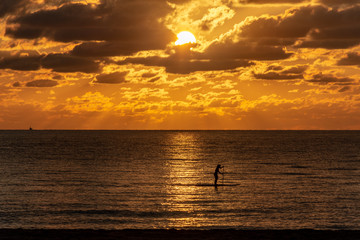 silhouette of a woman on a paddle board on the ocean at sunrise