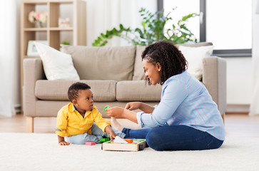 childhood, kids and people concept - happy african american mother and her baby son playing...