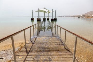 Fototapeta premium Path leading into the water on a sandy beach at the Dead Sea during a sunny day. Taken in Ein Bokek, Israel.