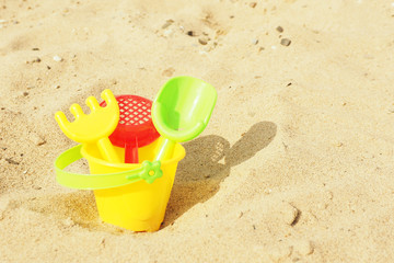 Children's toys shovel, rake and sieve in a bucket on the sand...