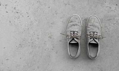 camouflage pair of old rundown shoes on concrete background with copy space