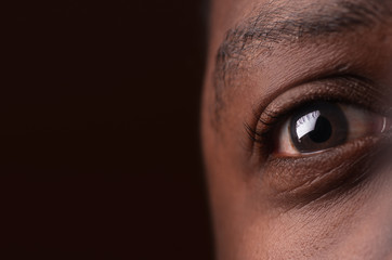 close up of african american eye on dark brown background