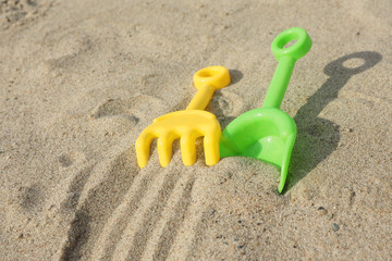 Fototapeta na wymiar Children's toys shovel, rakes and traces of them in the sand...