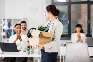 business, job and quit concept - female office worker with box of personal stuff and happy smiling colleagues applauding