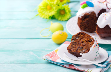 Easter cake on a white plate with colorful eggs. Blue wooden background. Copy space.