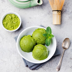 Green tea matcha ice cream scoop in white bowl. Grey stone background. Top view.