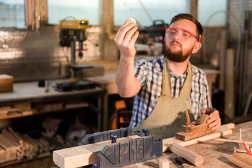 Working days of a professional carpenter in a home workshop, a craftsman at his workplace holds sawdust in his hand