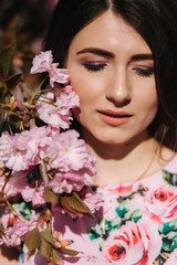 Naklejka premium Close up of beautiful woman near the pink tree with makeup close her eyes
