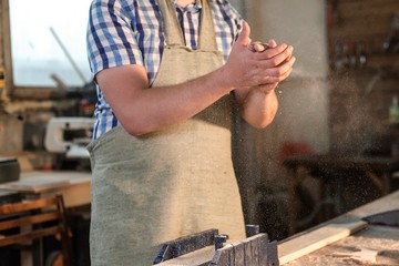 Bearded carpenter master have tossed. the hands of sawdust, dust flying in different directions