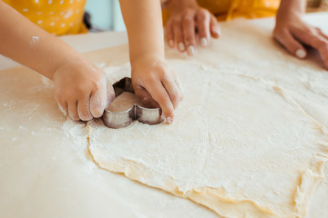 cropped view of daughter using heart shaped dough mold