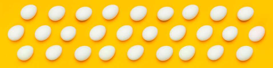 Pattern from White chicken eggs on yellow background top view flat lay copy space. Creative food...