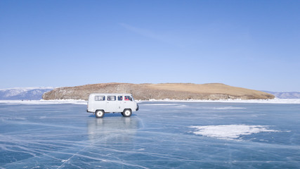 The old car moves on the ice of lake Baikal during the tour. A winter journey in Russia