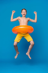 Happy child boy in swimsuit jumping with swimming ring © Prostock-studio