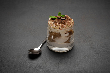 portion of Classic tiramisu dessert in a glass on concrete background