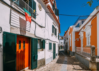 Small narrow cobblestone alley street between whitewashed houses and walls in old town Cascais, Portugal